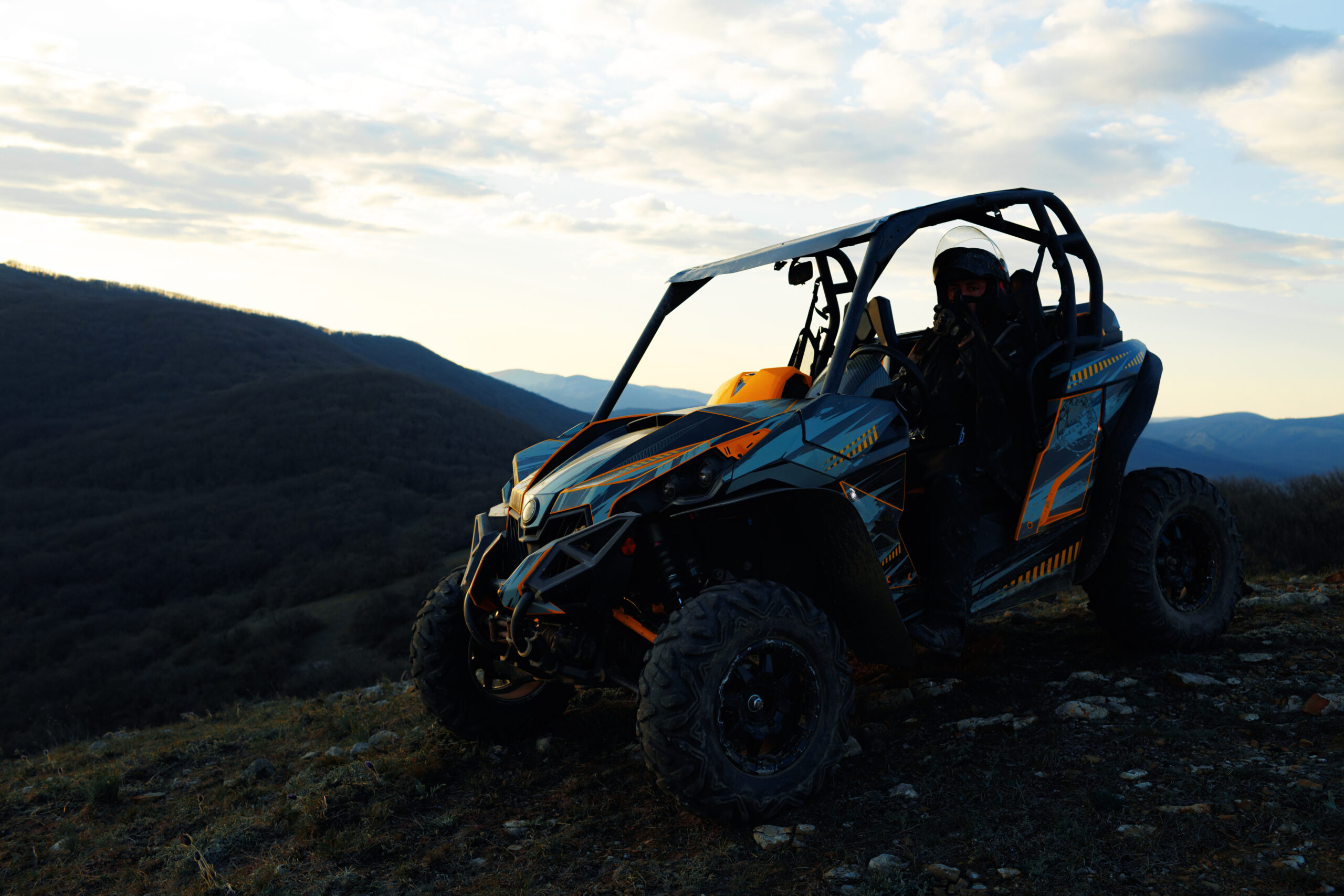 Man in helmet sitting on ATV quad bike in mountains on race